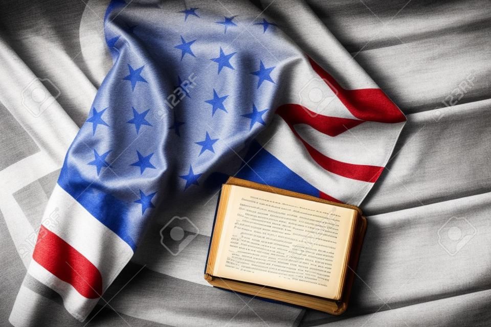 bandera de EE.UU. envejecida y libro. Libro que pone al lado de la bandera nacional. La ley le protegerá. En Dios confiamos.