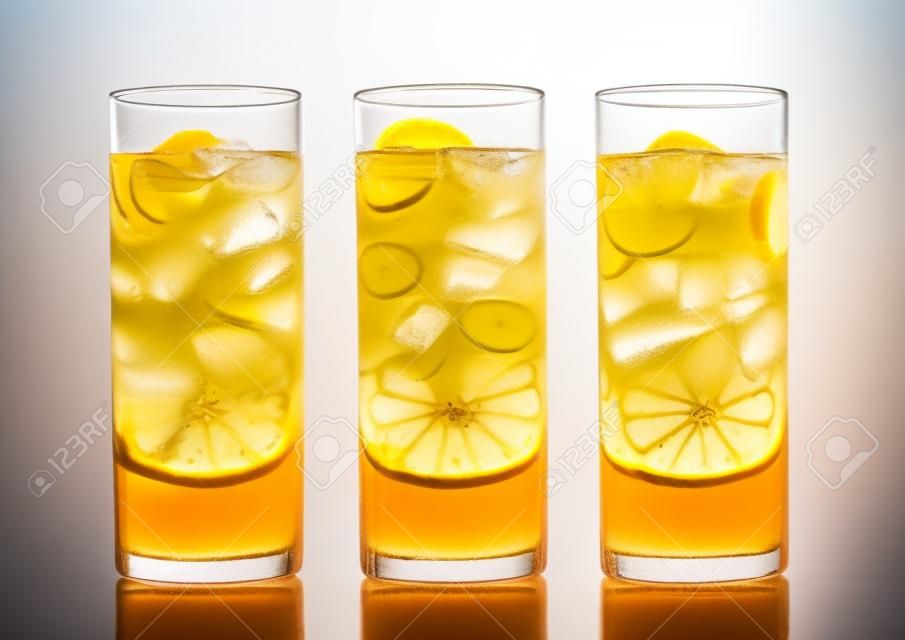 Lemonade drink with cola and orange soda soft drink with ice cubes on white in highball glasses.