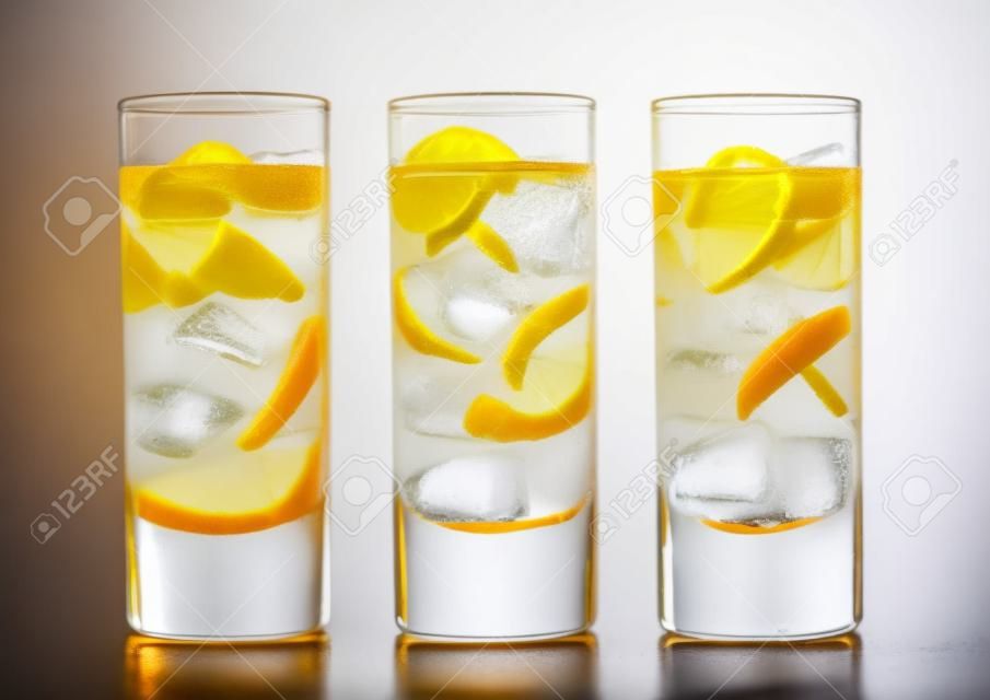 Lemonade drink with cola and orange soda soft drink with ice cubes on white in highball glasses.