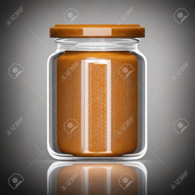 Transparent glass jar with peanut butter.
