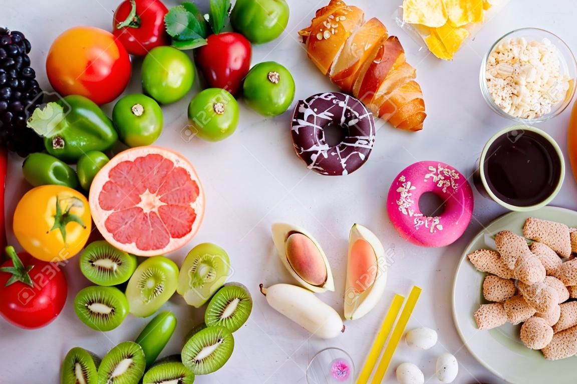 Gesundes und ungesundes Lebensmittelkonzept. Draufsicht auf schnelles und süßes Essen im Vergleich zu Obst und Gemüse