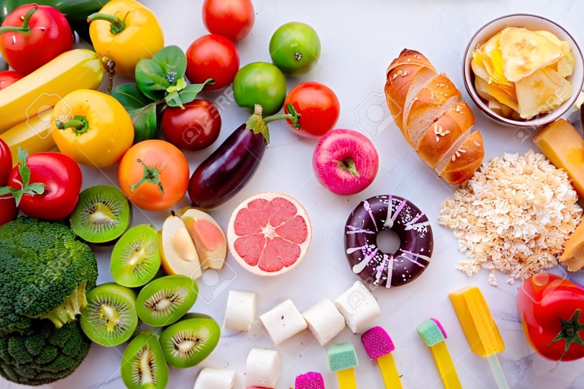 Concepto de alimentos saludables y no saludables. Vista superior de comida rápida y dulce frente a frutas y verduras.