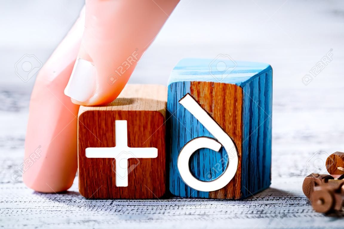 Gender Icon For Female On A Wooden Block Arranged By One Finger Next To The Male Sign On A Table