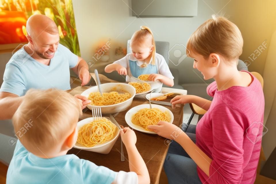 집에서 함께 볼로네제 스파게티를 즐기는 영국 가족. 그들은 아기 좌석에 여자 아기와 함께 식탁에 앉아 있습니다.