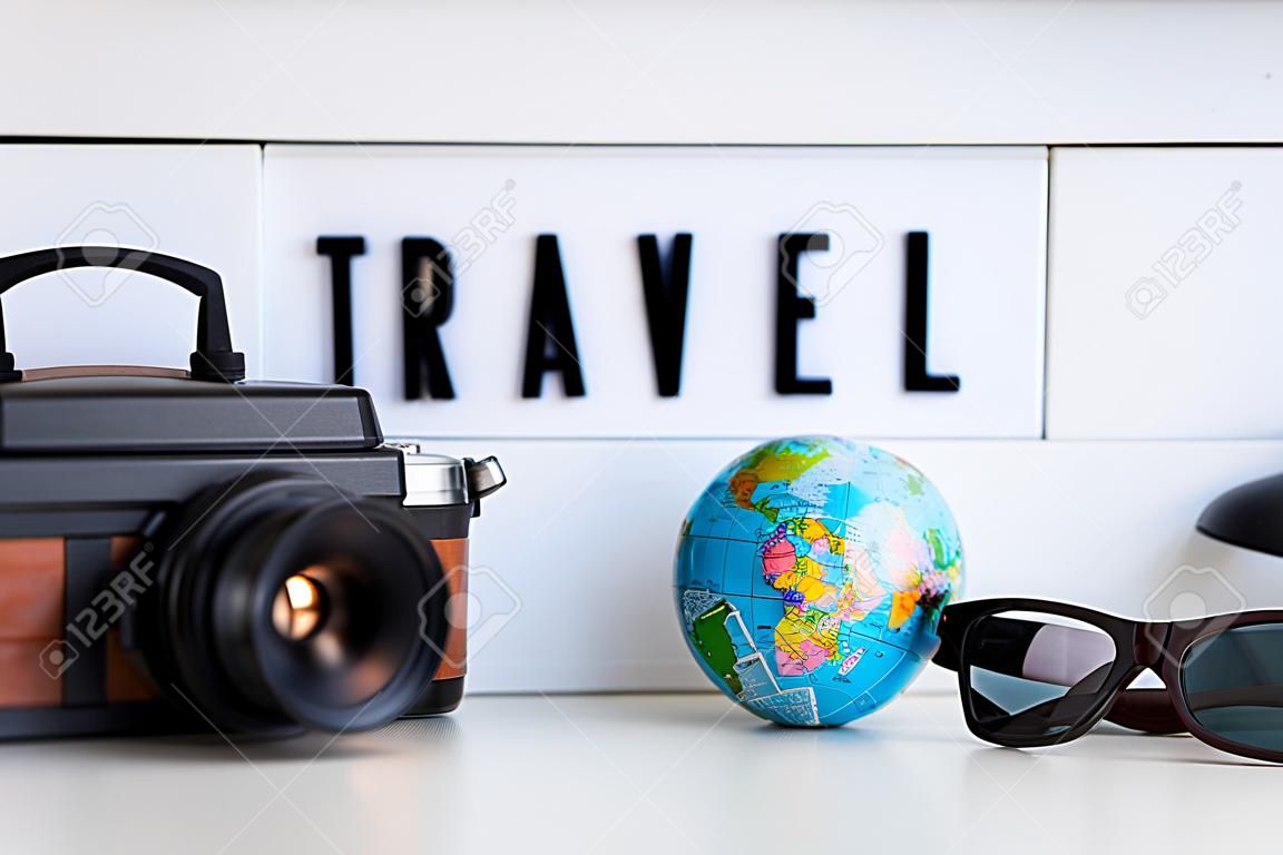 close up of travel objects and devices over retro light box with travel hash tag