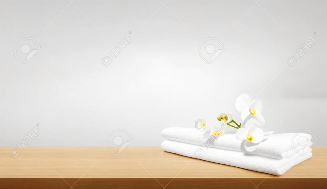 Serviette de spa pliée blanche et fleurs d'orchidées sur table en bois