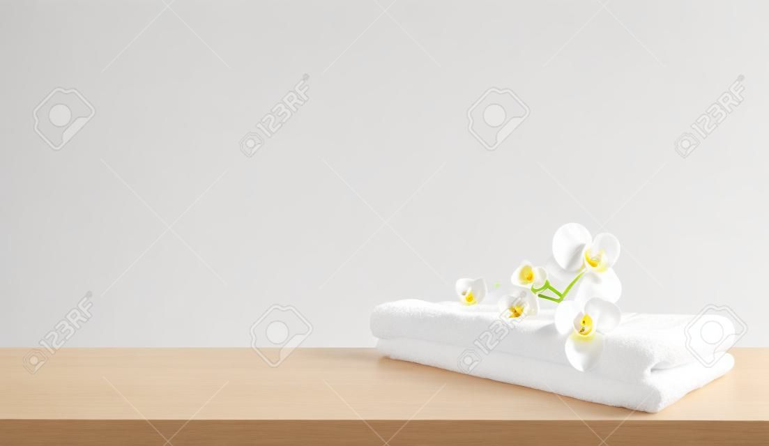 Serviette de spa pliée blanche et fleurs d'orchidées sur table en bois