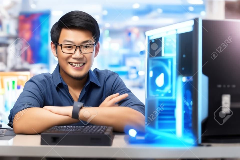 Joven dueño de la tienda asiática trabaja en almacén de la computadora, la reparación de la computadora y la adición de ram para PC. Retrato de hombre sonriente a la cámara
