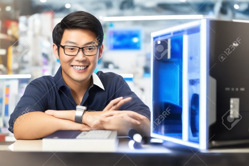若いアジア店所有者のコンピューター店で働いて、コンピューターの修理、pc に ram を追加します。カメラで笑顔の男のポートレート
