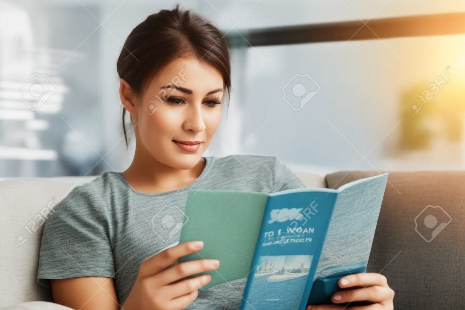 Woman Reading Travel Flye sur canapé à la maison