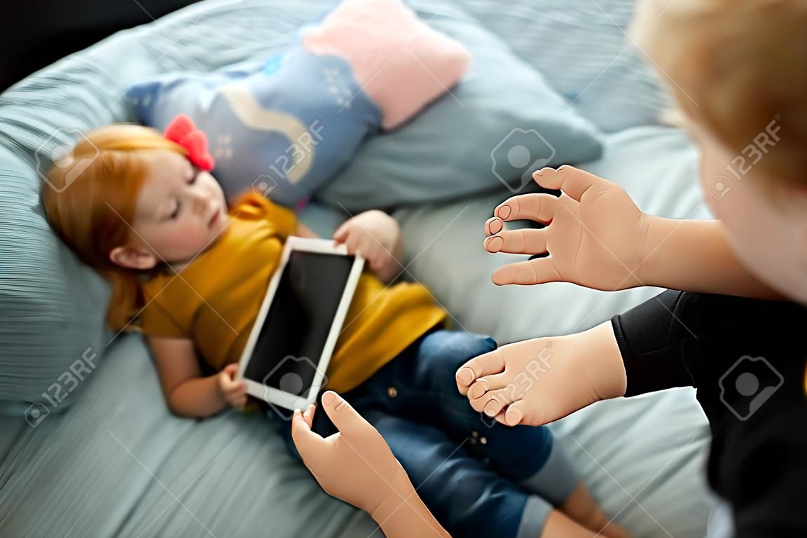 Kleines rothaariges Mädchen, das zu Hause Cartoons mit Tablet anschaut