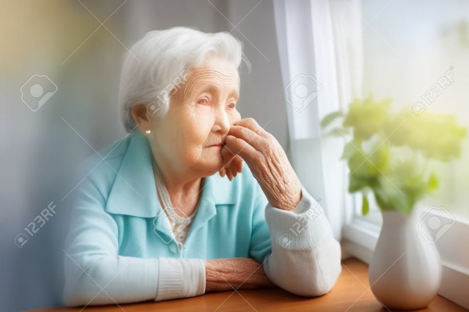 Une femme âgée regarde tristement par la fenêtre.