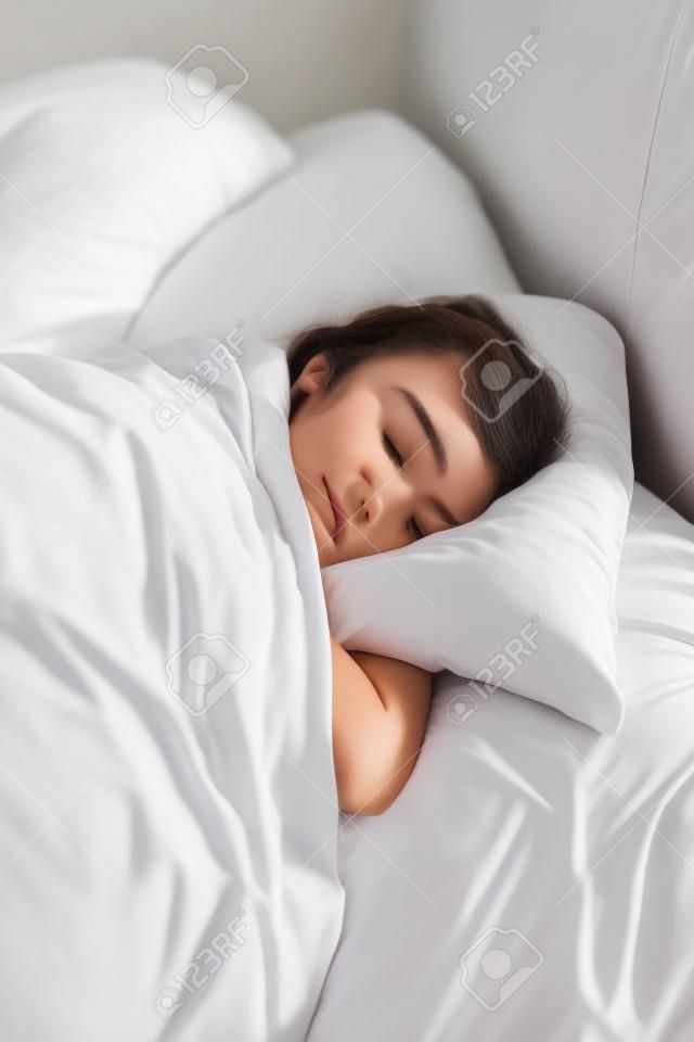 Mujer joven duerme en primer plano de la cama. Mujer morena durmiendo abrazo almohada