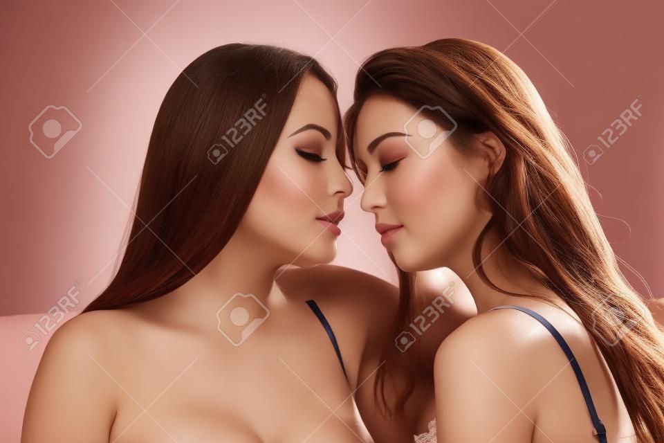 Dos hermosas mujeres jóvenes vestidos de lencería en estrecho contacto