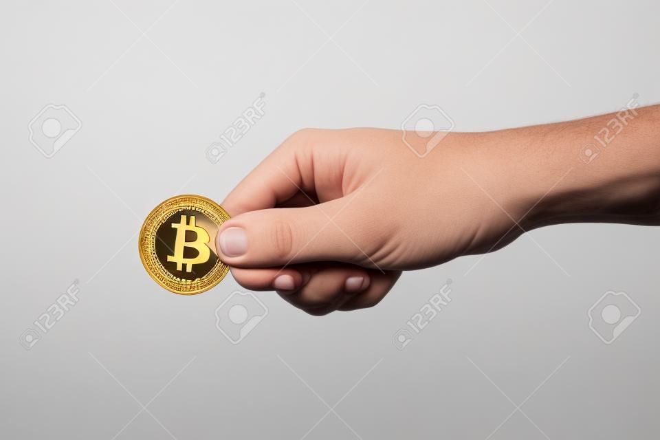 Man's hand holds a gold coin bitcoin coin. Isolated on white