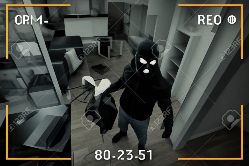 A man in a black mask is trying to rob a house. simulation of recording from a surveillance video camera. Robbery of a private house. Criminal concept, apartment theft. black and white camera recording effect