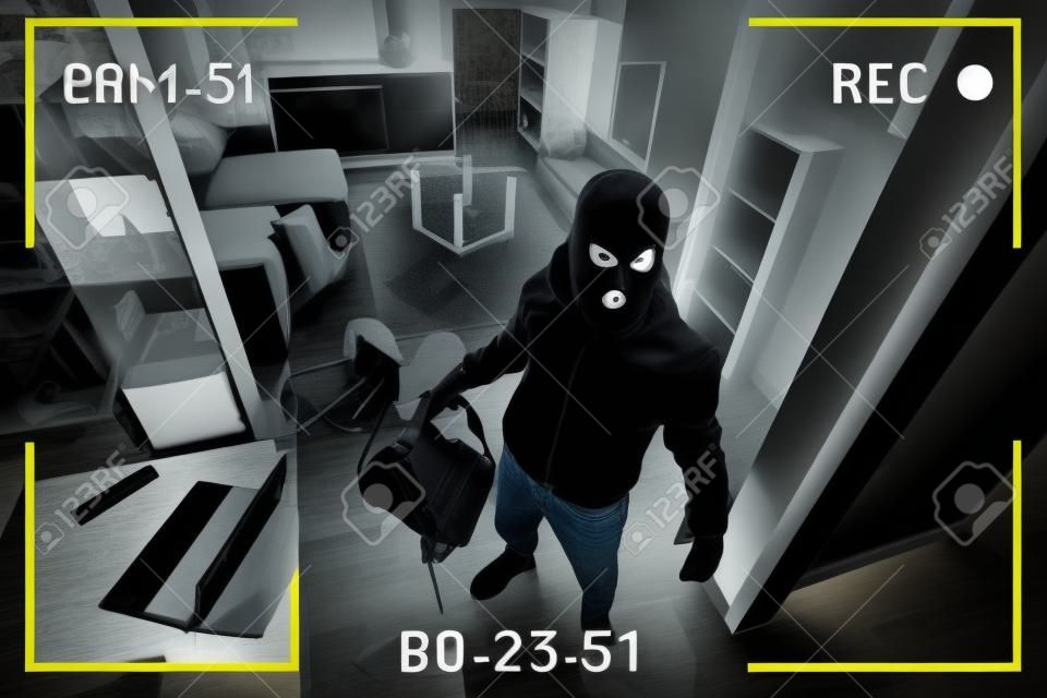 A man in a black mask is trying to rob a house. simulation of recording from a surveillance video camera. Robbery of a private house. Criminal concept, apartment theft. black and white camera recording effect