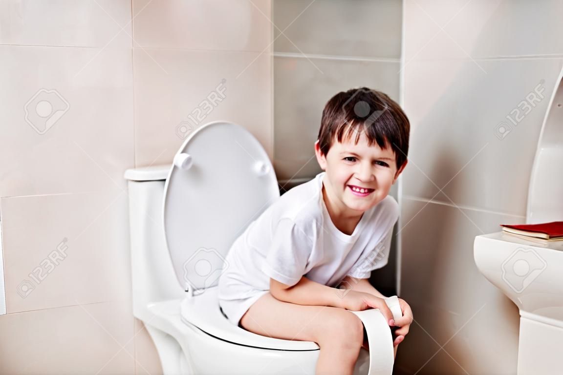 Menino de 7 anos de idade, sentado no banheiro.