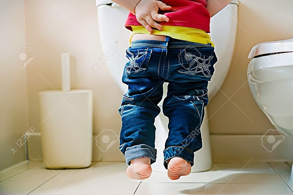 トイレに小さな 7 歳の少年。彼の足にビューを低