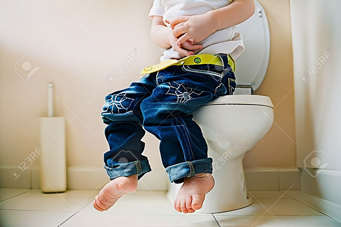 Little 7 years old boy on toilet. Low view on his legs