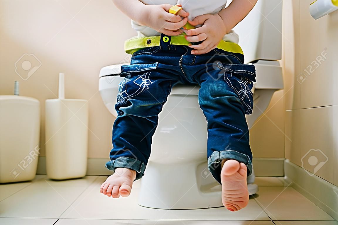Little 7 years old boy on toilet. Low view on his legs
