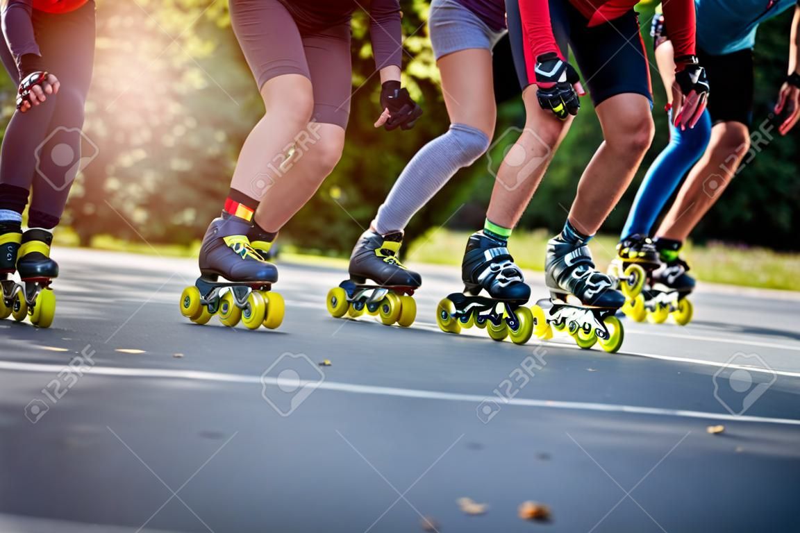 Patinadores de rolos em linha que correm no parque na estrada do asfalto