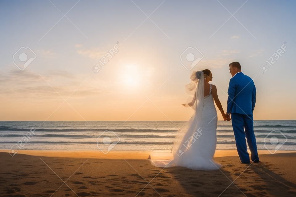 Hochzeit ein verheiratetes Paar, Braut und Bräutigam, bei Sonnenuntergang an einem wunderschönen tropischen Strand zusammen