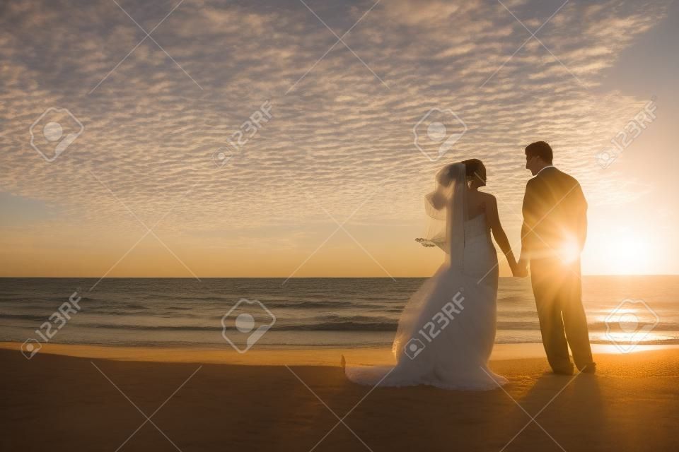 Casamento de um casal, noiva e noivo, juntos ao pôr do sol em uma bela praia tropical