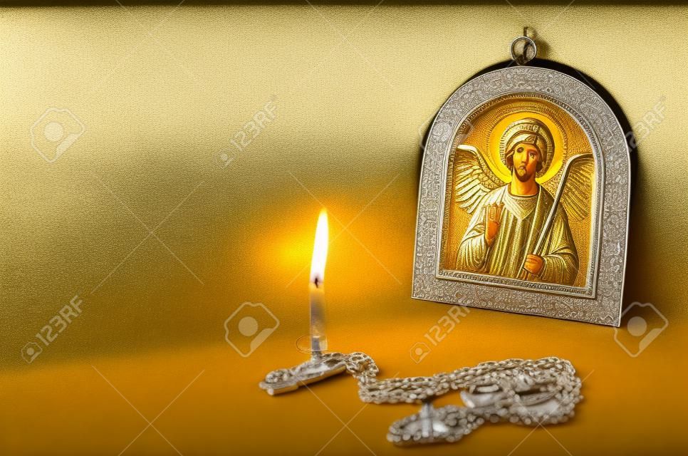 Icon van de Aartsengel Michael met zilver en vergulding, een borstkruis en een brandende kaars. Grote zilveren borstbeenkruis en massieve keten. Orthodox christendom.