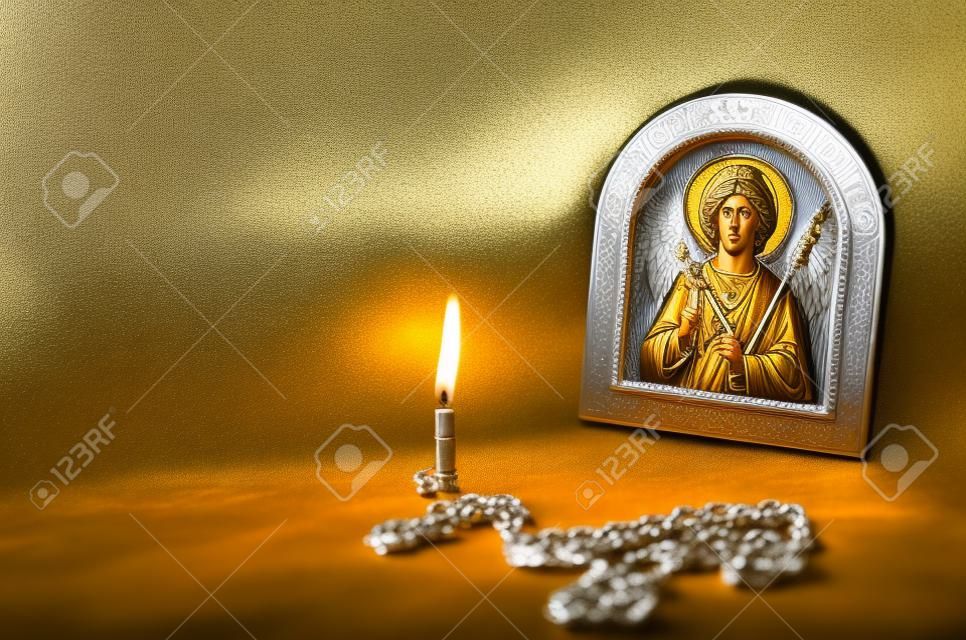 Icon van de Aartsengel Michael met zilver en vergulding, een borstkruis en een brandende kaars. Grote zilveren borstbeenkruis en massieve keten. Orthodox christendom.