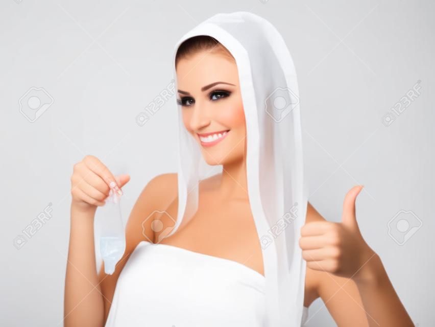 漂亮的女人拿著避孕套，給豎起大拇指在白色背景