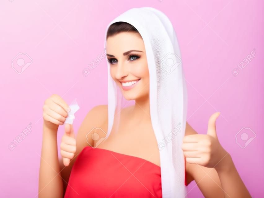 漂亮的女人拿著避孕套，給豎起大拇指在白色背景