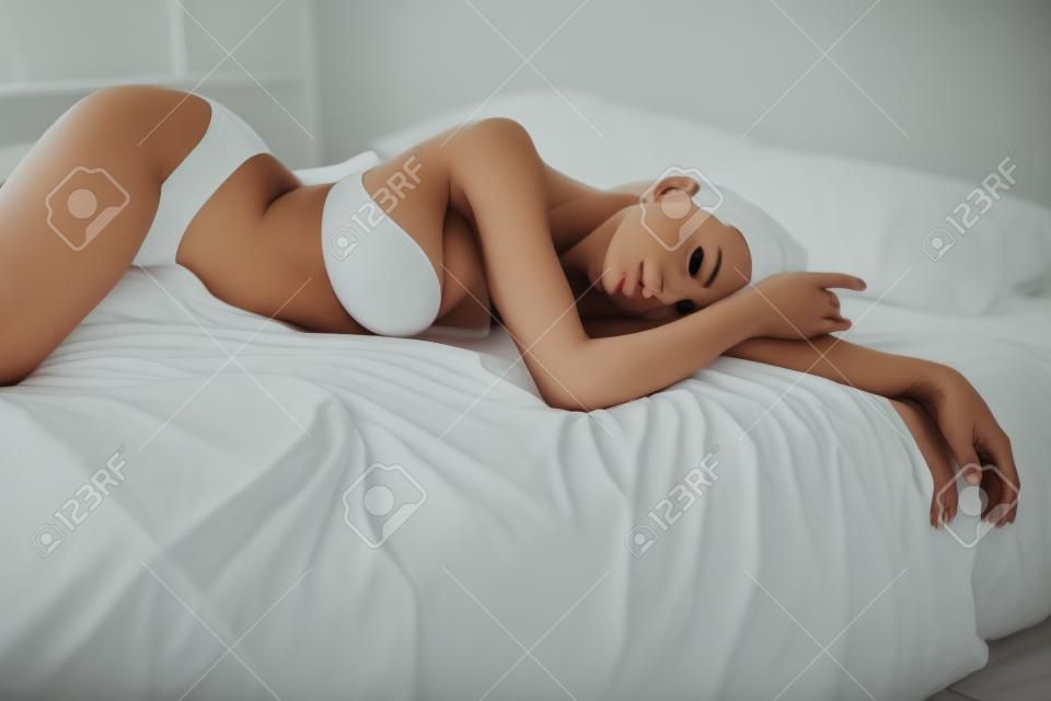 Schöne Frau in Unterwäsche liegt auf dem Bett im Schlafzimmer