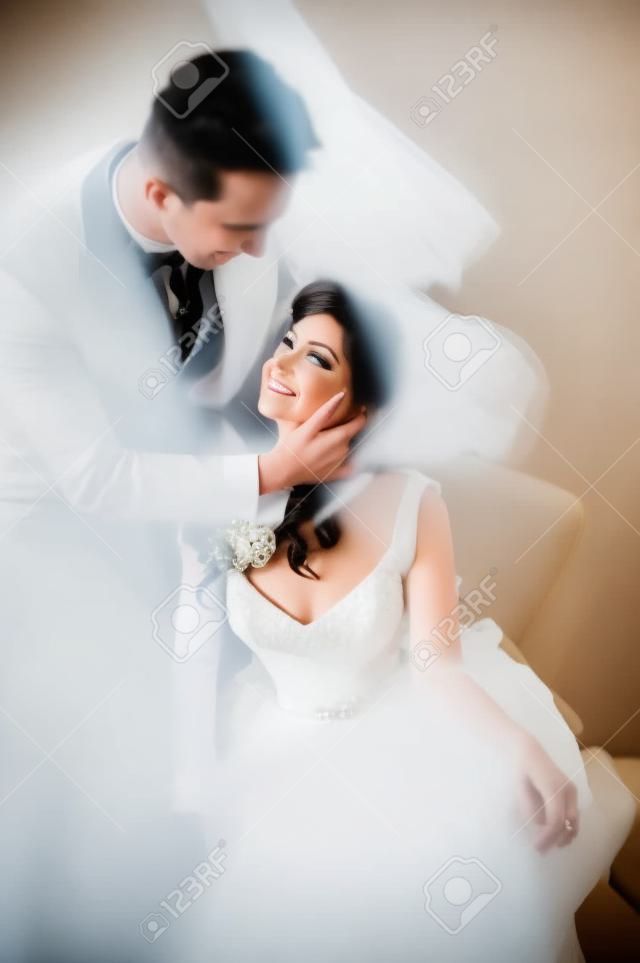 Stilvolle Braut und Bräutigam, die auf einem Stuhl im Hotel aufwerfen. Film