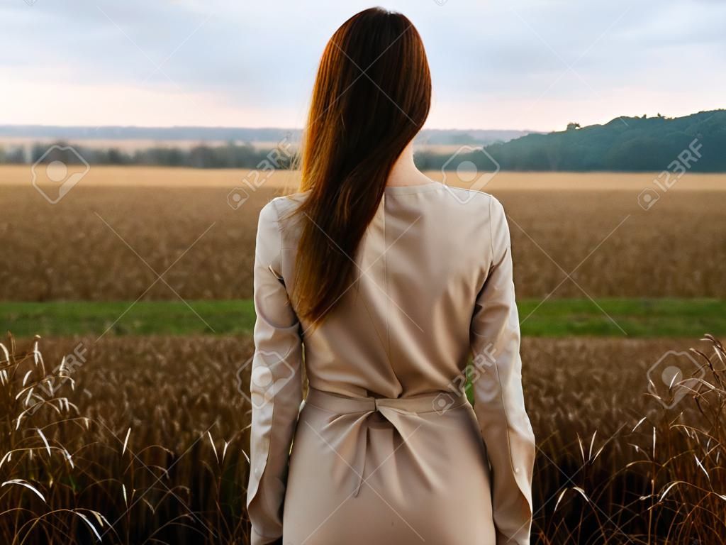 Back view of romantic woman outdoors in the fields
