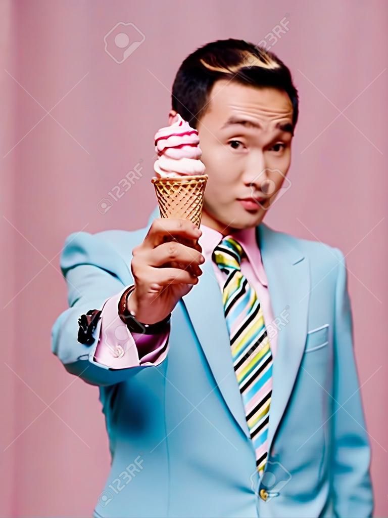 man asian appearance ice cream in hands blue suit pink background enjoyment