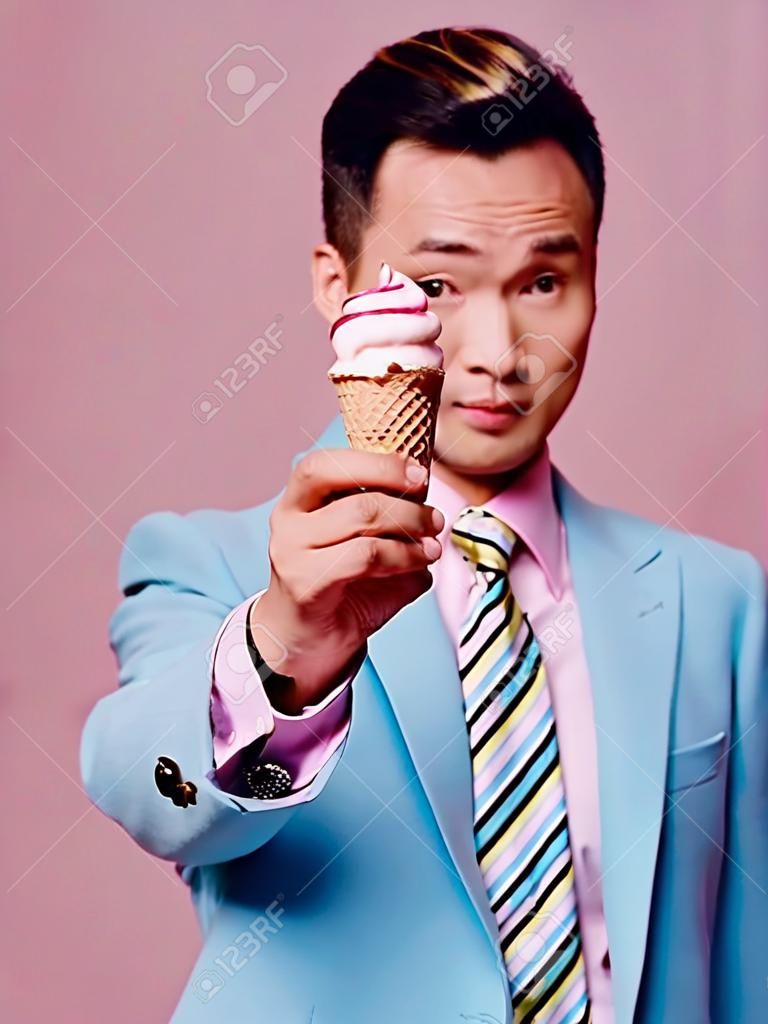 man asian appearance ice cream in hands blue suit pink background enjoyment
