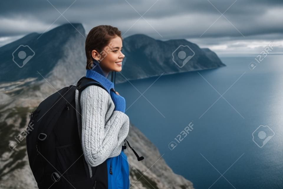 donna in un maglione con uno zaino in montagna all'aperto vicino al mare vista ritagliata
