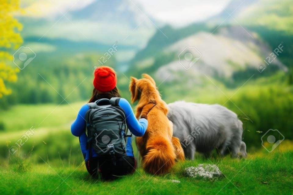 woman hiker with a backpack walks the dog in the mountains in nature