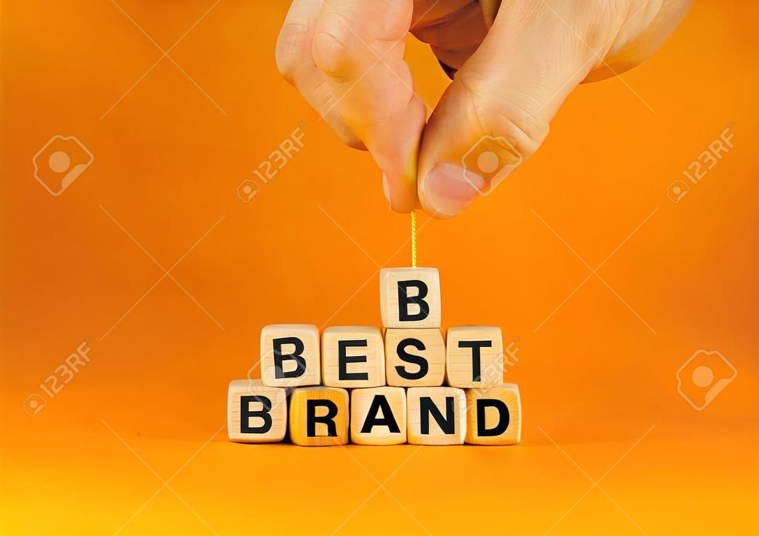 Build your best brand symbol. Concept words Best brand on wooden cubes. Businessman hand. Beautiful orange table orange background. Build your best brand and business concept. Copy space.