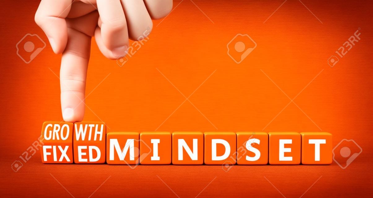 Growth or fixed mindset symbol. Concept words Growth mindset and Fixed mindset on wooden cubes. Businessman hand. Beautiful orange background. Business growth or fixed mindset concept. Copy space.