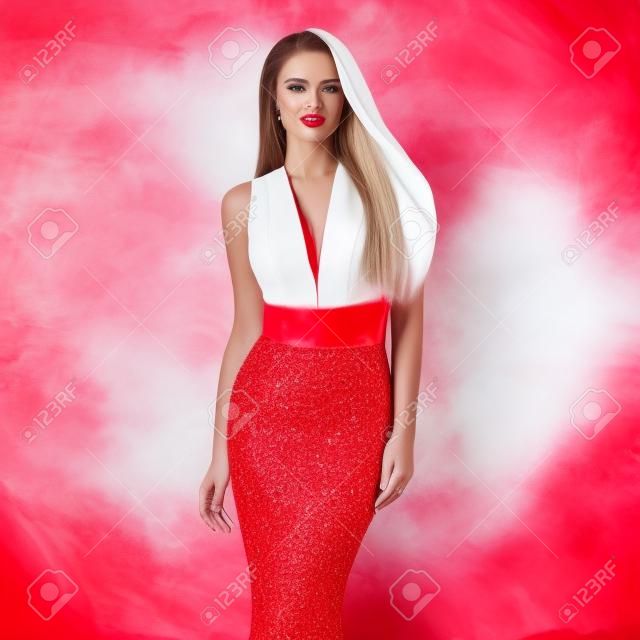 若い美しい魅力的な女性が長いエレガントな白いイブニング ドレスとスタイリッシュな赤い背景に赤い靴のポーズ