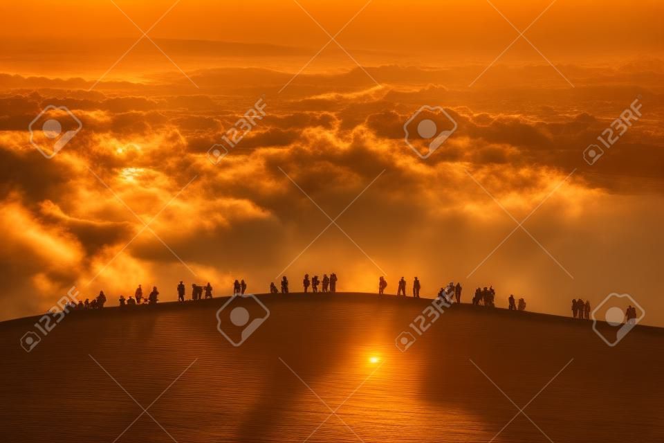 Gruppe von Menschen genießen den Sonnenuntergang auf dem Hügel