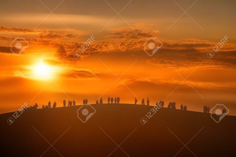 Gruppe von Menschen genießen den Sonnenuntergang auf dem Hügel