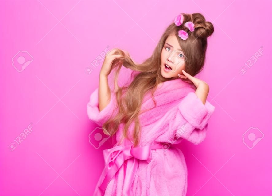 Young lady or teen girl in spa salon is surprised or frightened with her hair style condition. Acts like picky insta-model. Beauty concept on pink background