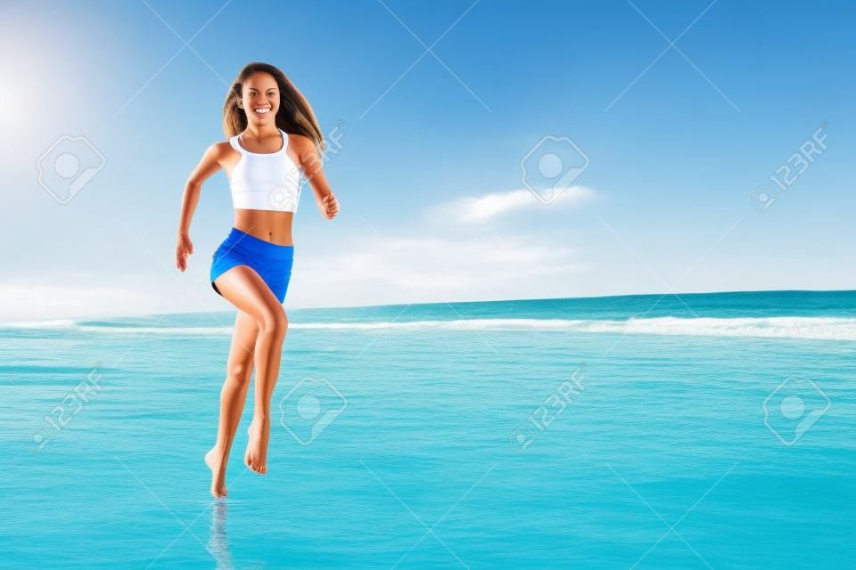 Ragazza a piedi nudi con un corpo snello che corre lungo la spuma del mare da una piscina d'acqua per mantenersi in forma e bruciare i grassi. Fondo della spiaggia con cielo blu. Fitness donna, attività sportiva da jogging durante le vacanze estive in famiglia.