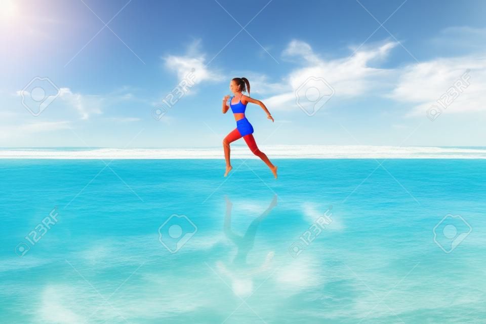 Niña descalza con cuerpo delgado corriendo a lo largo de las olas del mar junto a la piscina de agua para mantenerse en forma y quemar grasa. Fondo de playa con cielo azul. Fitness femenino, actividad deportiva para correr en vacaciones familiares de verano.