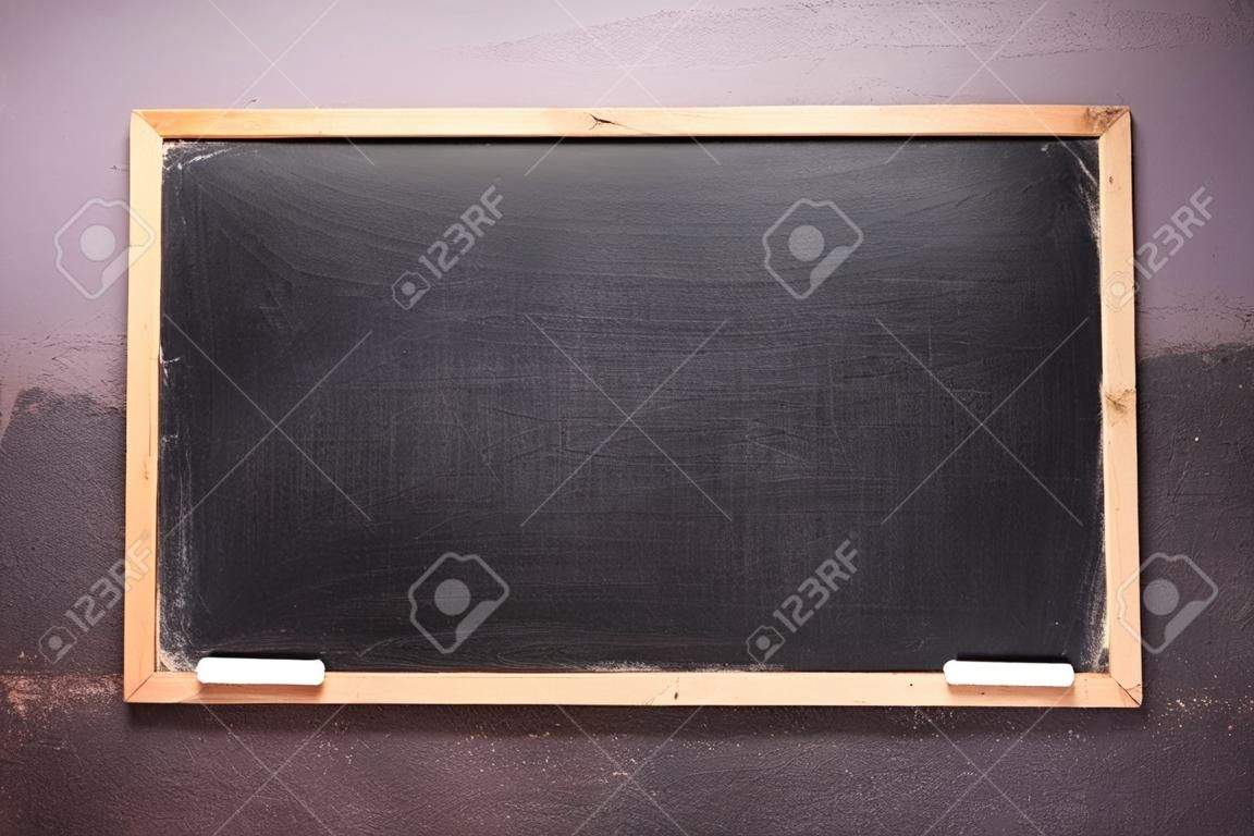 Empty small blackboard with dust and chalk on the wall