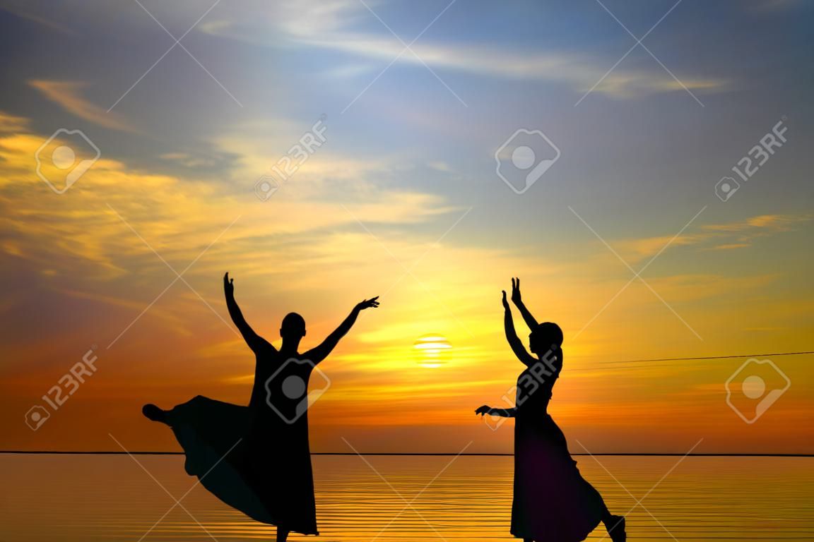 Two silhouette dancers in front of the sunset
