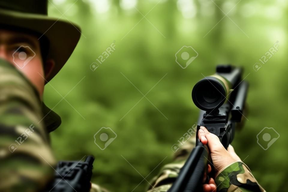 jagen, oorlog, leger en mensen concept - close-up van jonge soldaat, ranger of jager met pistool in het bos